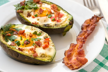 Eggs baked in avocado with bacon, red paprika and chive.