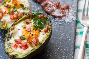 Eggs baked in avocado with bacon, red paprika and chive.