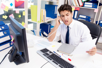 Businessman working in the office with piles of books and papers