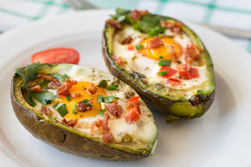 Eggs baked in avocado with bacon, red paprika and chive.