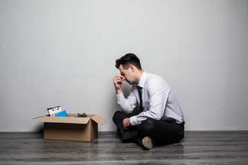 Obraz premium Fired frustrated man in suit sitting on floor in office. Sad