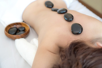 beautiful and healthy young woman  during a back stone therapy massage in spa salon