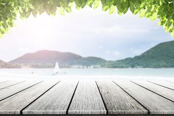 Empty wooden table and leaves with party on beach blurred background in summer time.