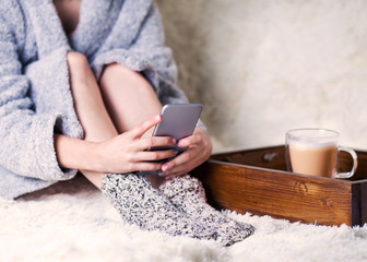 the girl is sitting with the phone in her hands. Breakfast in bed