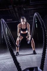  Battle ropes session. Attractive young fit and toned sportswoman working out in fitness  training gym © lordn