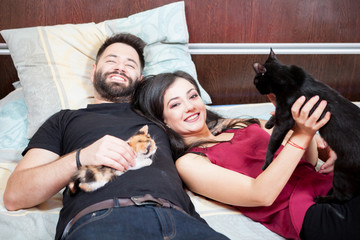 Inlove couple on the bed with their cats. Relax and love. Animal care. Animal lovers