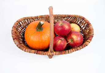 Basket full of apples and a pumpkin on a white background
