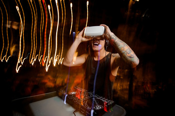 Young DJ in virtual reality glasses plays the track in club