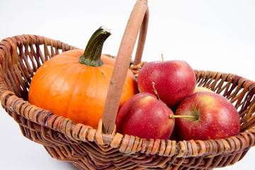 Basket full of apples and a pumpkin on a white background