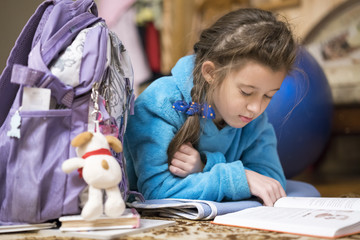Fototapeta na wymiar Child reading book at home. Girl doing homework