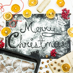 Fototapeta na wymiar inscription Christmas on a black board sprinkled with flour among the Christmas decor, ginger biscuits and dried oranges
