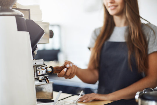 Close Up Of Female Barista Grinding Coffee To Make A Perfect Espresso Cup In A Bright Cafe On A Sunny Winter Day.