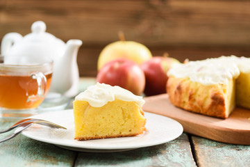 Traditional English cake with apples and whipped cream served with tea on blue wooden background