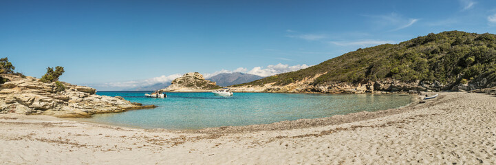 Fototapeta na wymiar Boats in a small rocky cove with sandy beach in Corsica