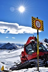 A snow groomer after working on the snowpark with warning sign in the foreground