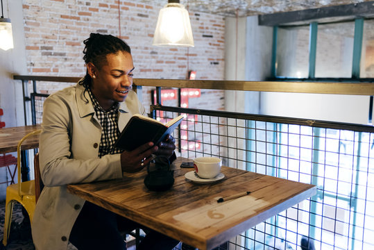 Young stylish man reading diary in cafe