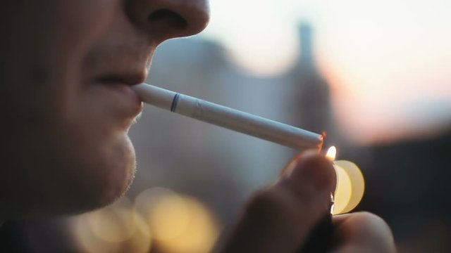 Man lighting a cigarette against a urban background slow motion closeup addiction bad habbit unhealthy
