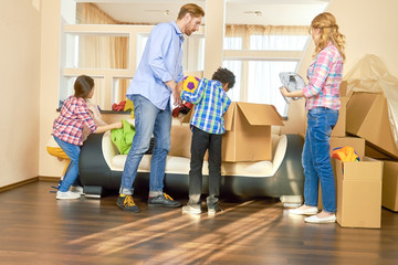 Family indoors, relocation. Parents with kids, cardboard boxes.