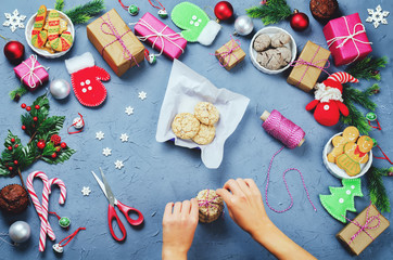 Christmas background with gifts, cookies, Christmas decoration and woman's hands holding cookies