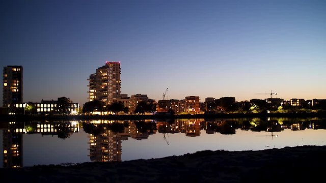 Quiet waters outside the city of Copenhagen at night, city with lights and buildings reflecting in the surface