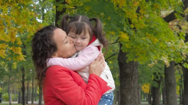 Woman with child in the park. Little girl hugging mother.