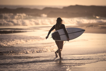 Female surfer running on the beach with her surfboard