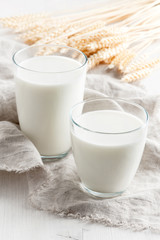 Two various glasses with milk on the white wooden table