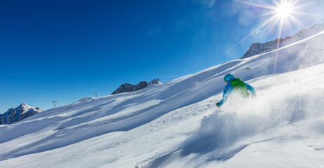 Young man skier running downhill in powder snow
