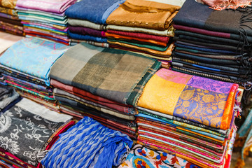 Many bright female scarfs and shawl close-up at shop