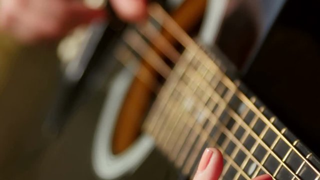 Woman playing acoustic guitar, closeup shot with selective DOF