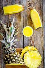 Freshly squeezed pineapple juice near fruit slices on wooden background top view