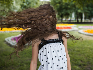 Summer happiness in motion. Strong wind. Unrecognizable teenage girl portrait, park background.
