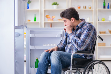 Young disabled injured man opening the fridge door 