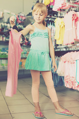 Portrait of girl choosing colored dress and wear in the shop