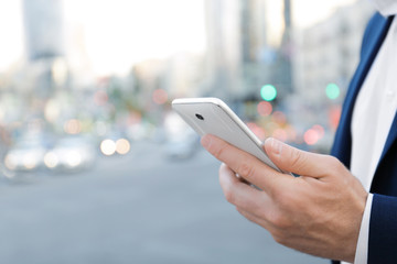 Elegant businessman using mobile phone outdoors, closeup