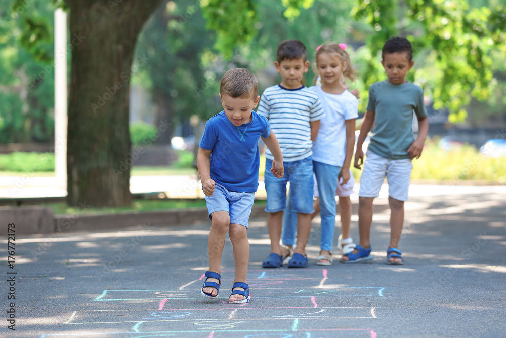 Wall mural little children playing hopscotch, outdoors