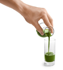 Woman pouring wheat grass drink into shot on white background