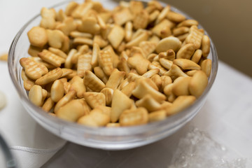 Bowl of mini cheddar cheese biscuits in a bowl on a white table top with  a table cloth