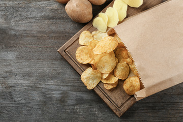 Board with crispy potato chips on wooden table