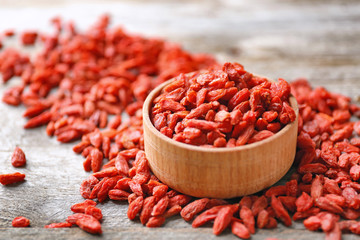 Bowl with red dried goji berries on wooden table