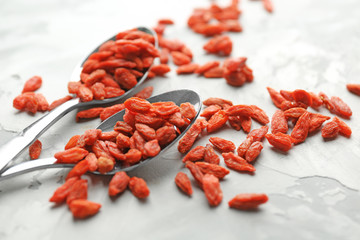 Spoons with red dried goji berries on grunge table