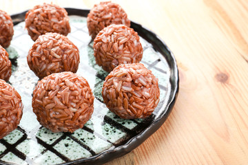 Plate with brown rice balls on table