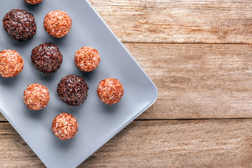 Plate with red and brown rice balls on wooden table