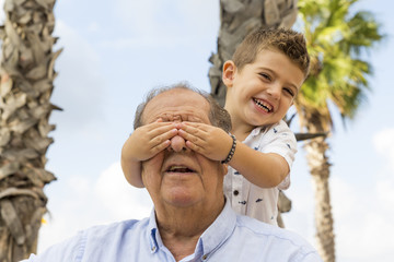 Grandson covering his granfather's eyes
