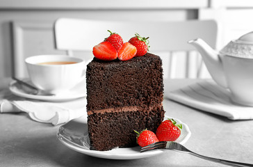 Plate with piece of delicious chocolate cake on table