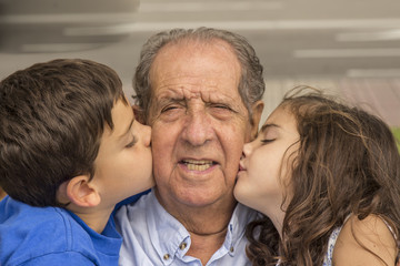 Grandchildren kissing their grandfather