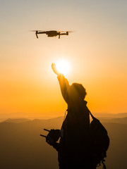 Silhouette of young man catching drone at sunset for photos and video making - Happy man having fun with new technology trends in mountains © Oleksandr