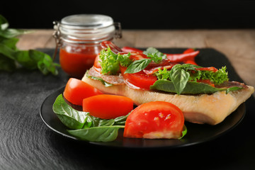 Plate with delicious sausage sandwich on table