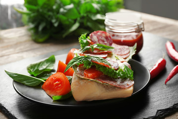 Plate with delicious sausage sandwich on table