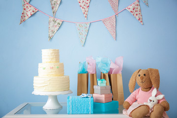 Baby shower gifts, cake and toys on table indoors